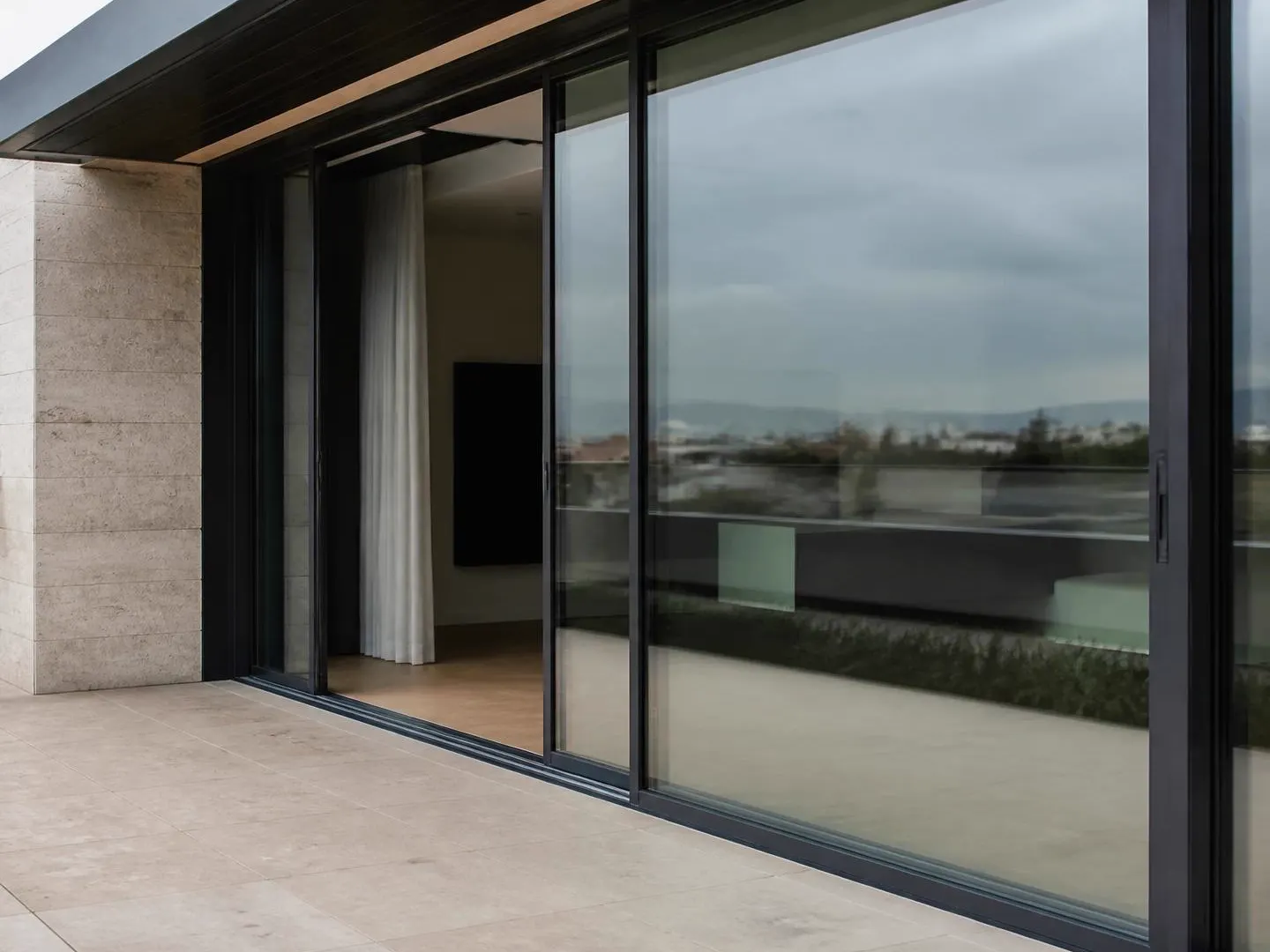 Modern bir terasta yatay olarak sürülen geniş cam balkon panelleri